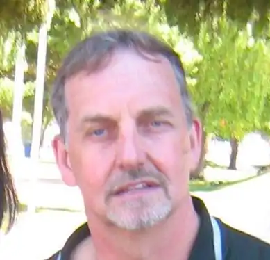 Portrait of a middle-aged man outdoors with trees in the background.