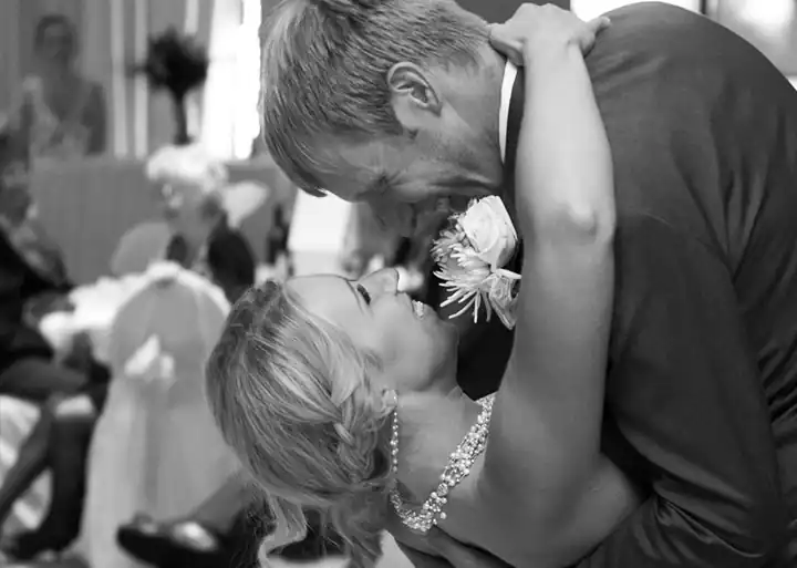 A joyful black-and-white photo of a bride and groom sharing a romantic dip during their wedding dance.