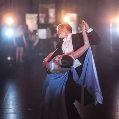 A couple performing an elegant dance dip under dramatic stage lighting.